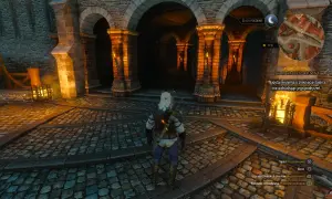 Geralt stoi przed arkadami, szukając skarbu hrabiego Reuvena. W tle widać pochodnie i kamienne mury.