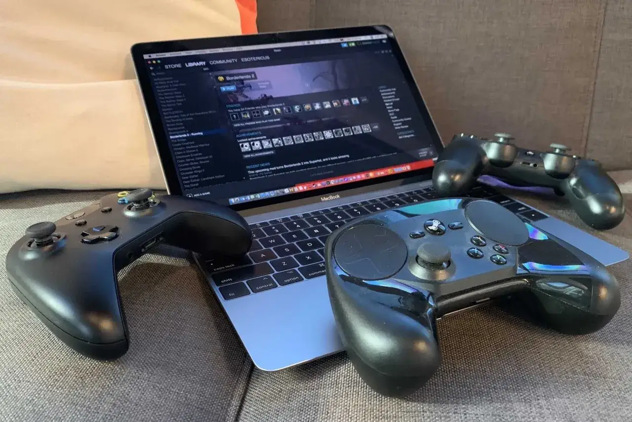 Gry na MacBooku: Borderlands 2 na ekranie, trzy kontrolery gotowe do akcji.